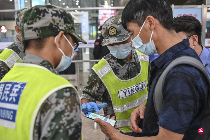 广州市从前晚10时起规定旅客须凭“健康码”绿码，并持有72小时内核酸检测阴性证明，才能离开广州。图为广州南站工作人员前天检查进站旅客的“健康码”及核酸检测信息。（香港中通社）