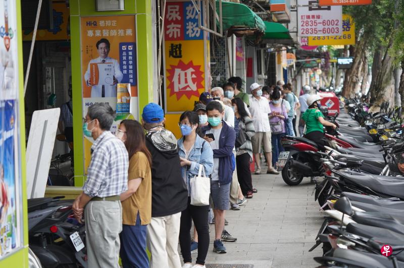 台湾的家用快筛试剂贩售实名制昨天上路，每人可依身份证字号尾数单、双号分流前往健保特约药局或偏乡卫生所购买。图为台北市一家药局外在开门前出现排队人潮。（中通社）