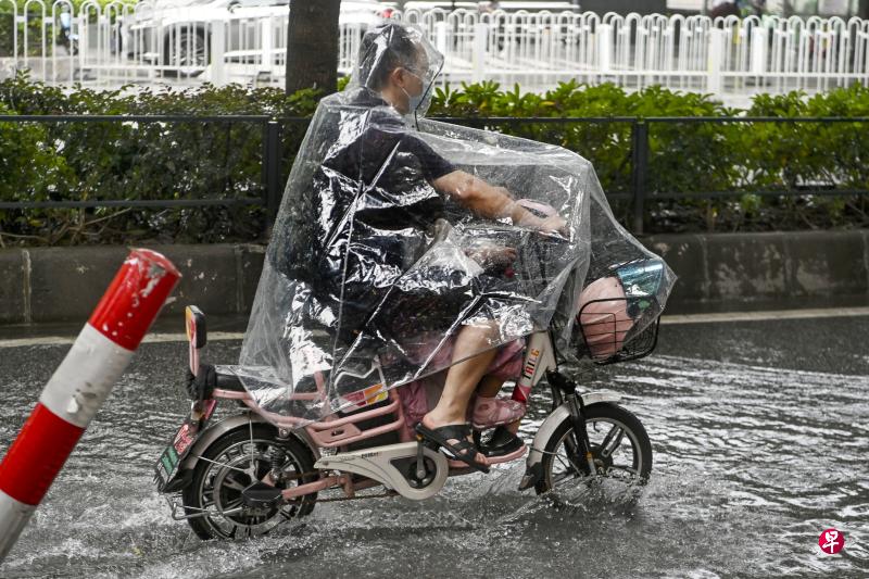 受台风“暹芭”影响，广州市城区昨天下暴雨，市民雨中出行。（中新社）