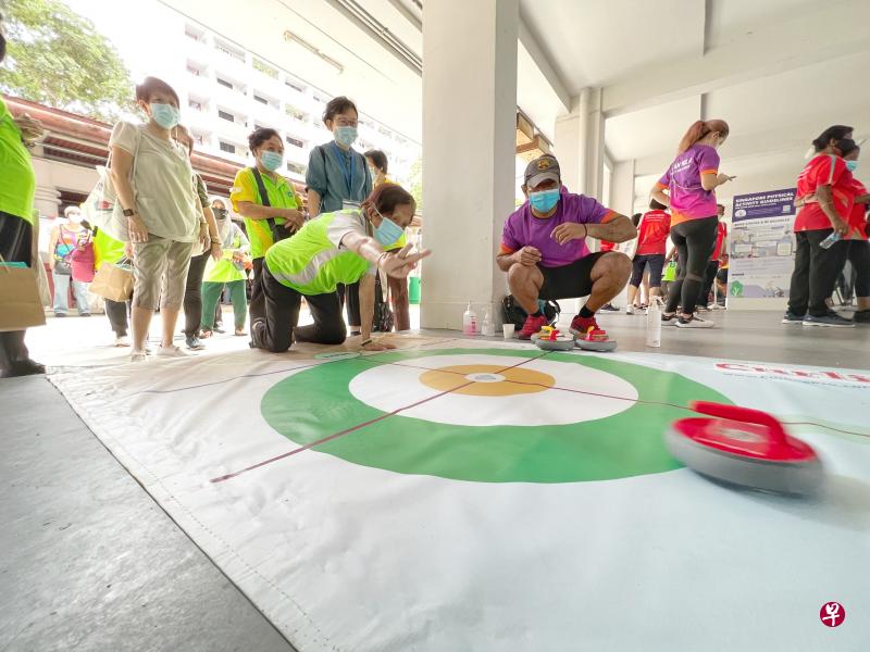 许多住在女皇镇一带的年长者星期六参观“共同推广健康长寿生活”展览，尝试新奇的旱地冰壶等运动。（龙国雄摄）