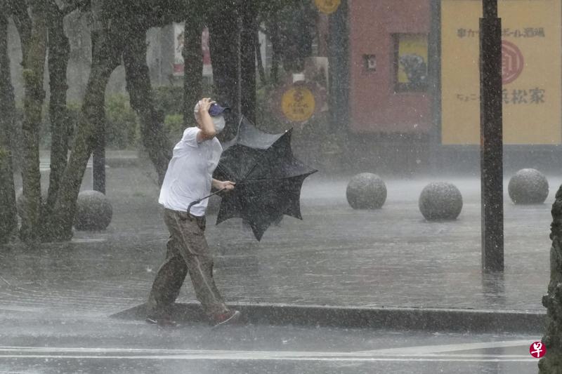 日本静冈县滨松市是遭热带风暴吹袭的地区之一，在暴雨中行走的男子就算备有雨伞也不管用。（路透社）