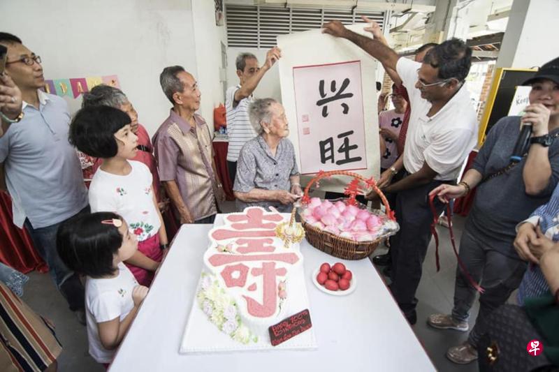 武吉巴督区议员穆仁理（右二）为庆祝百岁大寿的居民送上自己写的书法，作为生日祝福。（受访者提供）