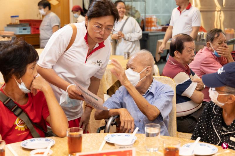 “让希望活下去”发起人潘迎芬，向居民梁耀忠解说如何使用购物券。（张思庆摄）