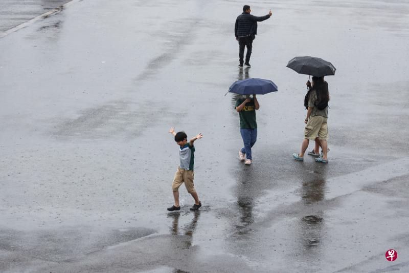 雨中玩乐，并非小孩的专利。（李冠卫摄）