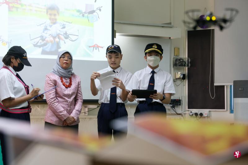 学生尹智宇（右一）操控无人机在模拟灾难现场中飞行，哈莉玛总统（左二）在旁观看无人机穿越障碍物的过程。（卓祾祎摄）