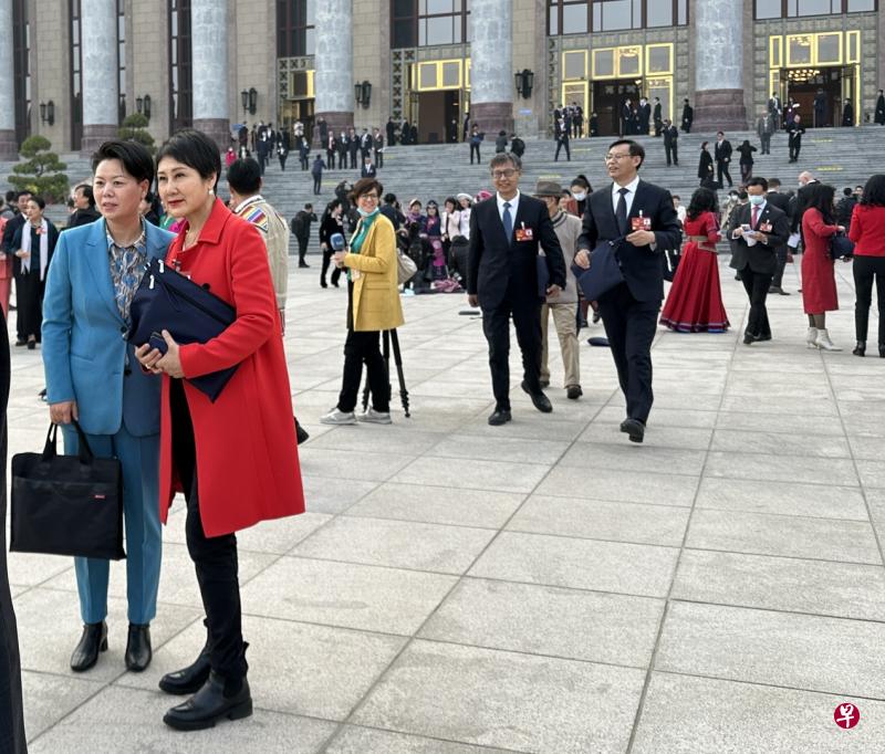 参加全国政协会议开幕式的委员们，走出人民大会堂后纷纷摘下口罩。身穿醒目红色外套的文艺界委员、演员张凯丽（左二）成为众人争相合影的对象。（陈婧摄）