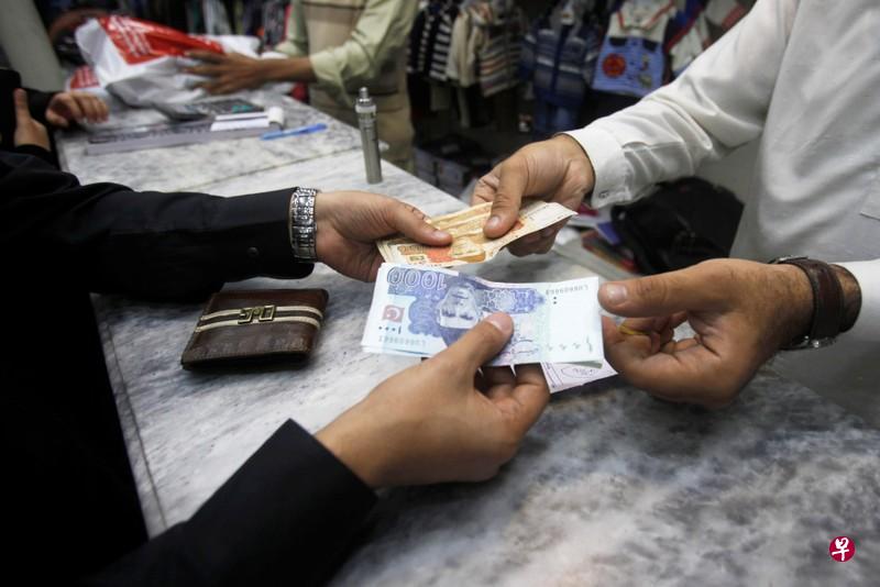 Men exchange Pakistani banknotes at a shop counter in Peshawar, Pakistan November 17, 2017. In recent years Pakistan's economy has benefited from improved security across the country and vast Chinese infrastructure investment after Beijing pledged $57 billion as part of its Belt and Road initiative. FILE PHOTO: REUTERS