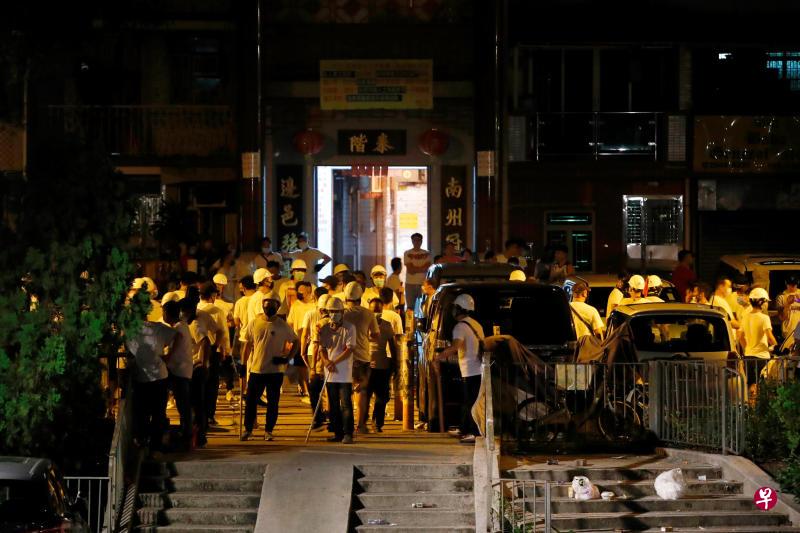 在香港西铁元朗站内袭击反修订《逃犯条例》的示威者后，白衫人众戴着头盔、口罩聚集在元朗站附近，部分人手中持有棍棒。（路透社）