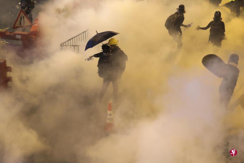 香港警方于晚上9时37分连续发射催泪弹驱散示威者。图为铜锣湾示威者身陷在催泪弹烟霾中。（美联社）