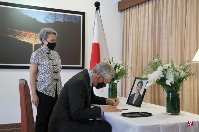 李显龙总理（右）7月12日上午到日本驻新加坡大使山崎纯的官邸，向日本前首相安倍晋三致敬并在吊唁册上留言。陪同他的是总理夫人何晶（左）。（通讯及新闻部提供） 