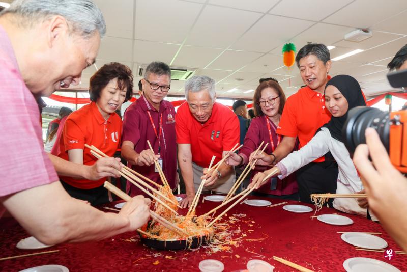 李显龙总理（左四）除夕早上到兀兰综合交通中心，同巴士车长、SMRT和陆路交通管理局管理层代表、工会成员一起捞鱼生。随行的有全国职工总会秘书长黄志明（右二）和会长雷家英（左二）。（卓祾祎摄） 